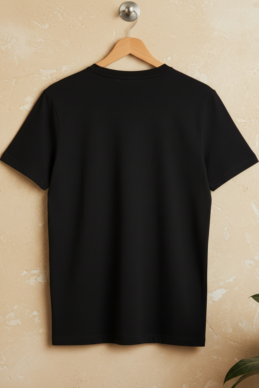 A plain black short-sleeve crewneck T-shirt hanging on a wooden hanger against a textured beige wall.