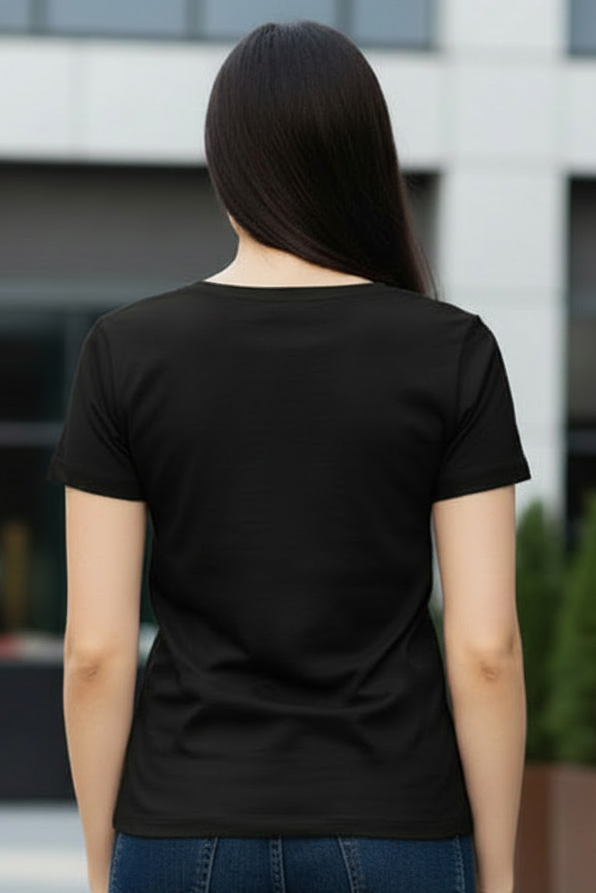 A woman viewed from behind wearing a plain black short-sleeve t-shirt and dark blue jeans, standing outdoors in front of a modern building with glass windows.