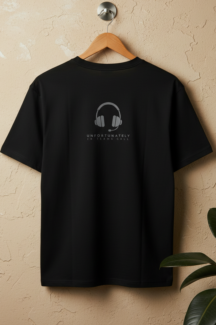 A black short-sleeve T-shirt hanging on a wooden hanger against a textured beige wall, with a small gray headphone graphic and the text 'UNFORTUNATELY NO TEACHER CALL' printed on the back. A plant leaf is visible in the lower right corner.